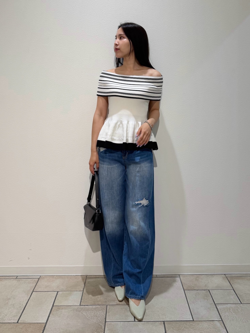 ブルー系のデニムパンツ、ブラック系のハンドバッグ、グリーン系のパンプスを着用したレディースの夏コーディネートの1枚目の写真