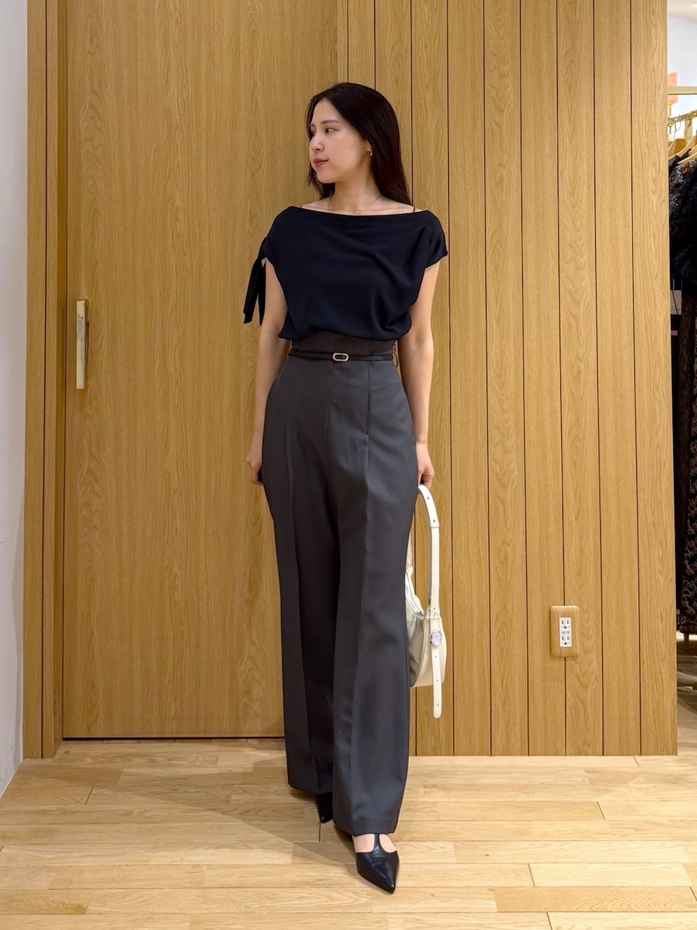 グレー系のその他パンツ、ブラック系のニット/セーター、ホワイト系のハンドバッグを着用したレディースの夏コーディネートの1枚目の写真