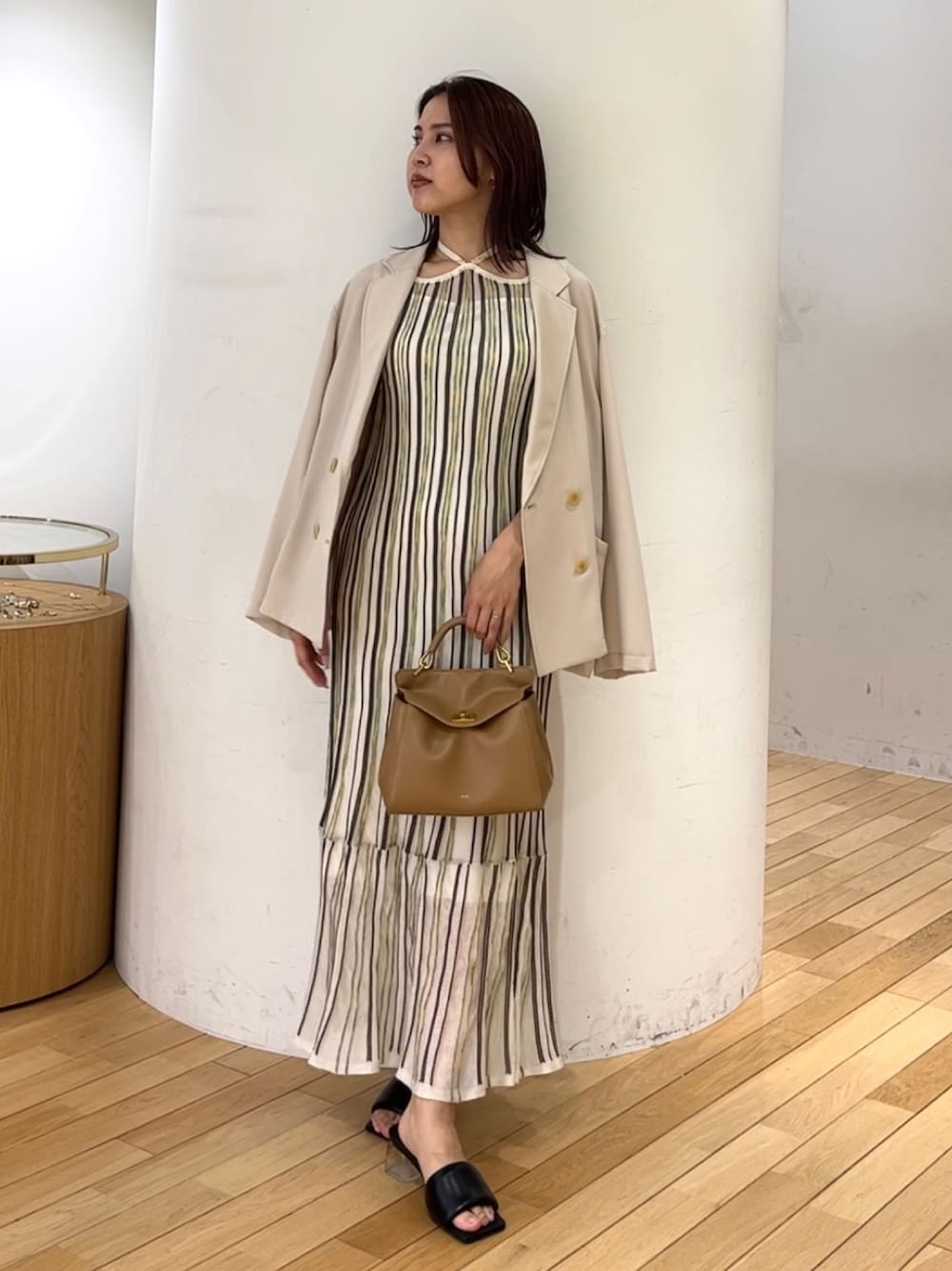 ブラウン系のハンドバッグ、ホワイト系のワンピース、ベージュ系のテーラードジャケットを着用したレディースの春コーディネートの1枚目の写真