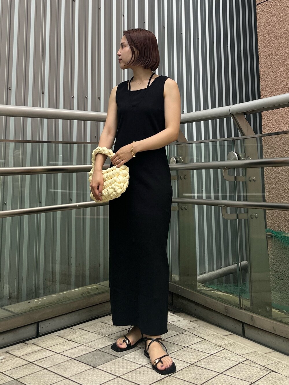 ブラック系のワンピース、ブラック系のサンダル、ホワイト系のハンドバッグを着用したレディースの夏コーディネートの1枚目の写真