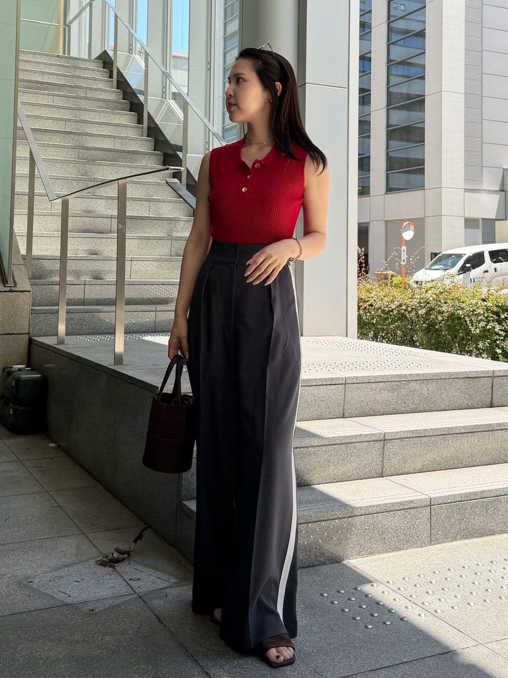 グレー系のその他パンツ、レッド系のニット/セーター、ブラウン系のハンドバッグを着用したレディースの春コーディネートの1枚目の写真