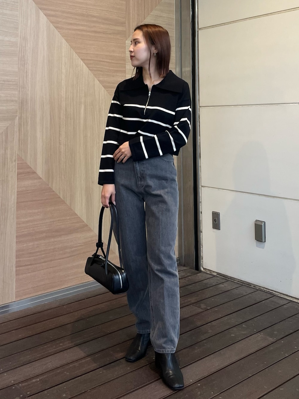 ブラック系のデニムパンツ、ブラック系のニット/セーター、ブラック系のショルダーバッグを着用したレディースの冬コーディネートの1枚目の写真