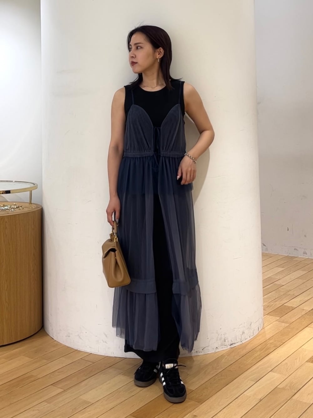 ブラウン系のハンドバッグ、ブラック系のスニーカー、ブルー系のワンピースを着用したレディースの夏コーディネートの1枚目の写真