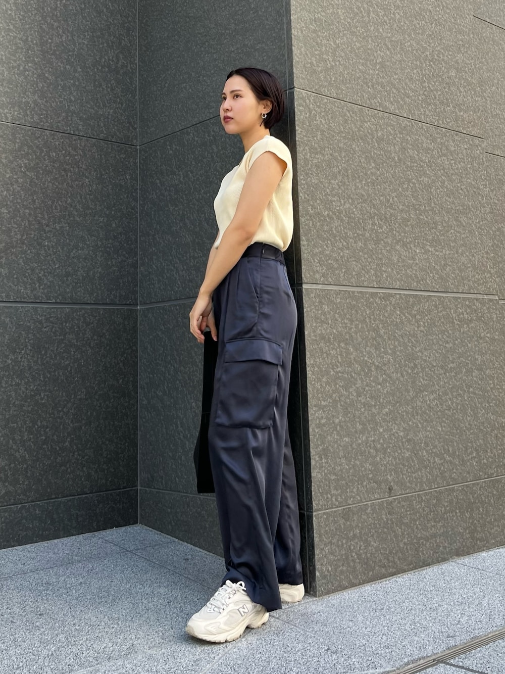 ブラック系のハンドバッグ、ブルー系のカーゴパンツ、ホワイト系のニット/セーターを着用したレディースの春コーディネートの1枚目の写真