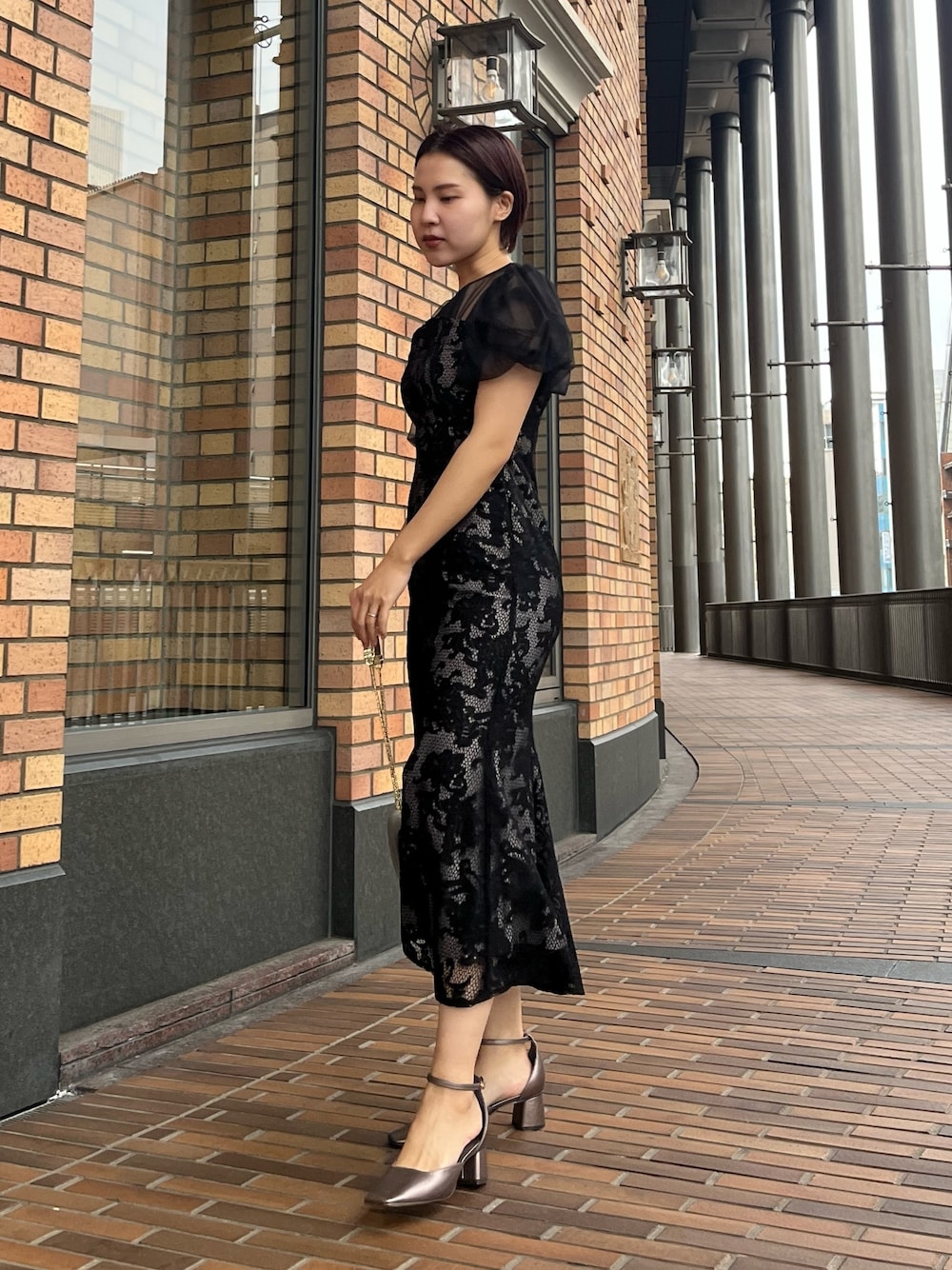 ブラック系のドレス、その他のパンプス、シルバー系のハンドバッグを着用したレディースの冬コーディネートの1枚目の写真