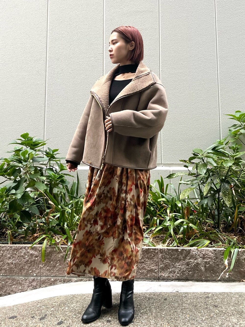 オレンジ系のスカート、ベージュ系のムートンコート、ブラック系のニット/セーターを着用したレディースの秋コーディネートの1枚目の写真