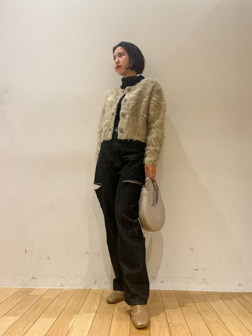 ホワイト系のハンドバッグ、ブラック系のデニムパンツ、ベージュ系のブーツを着用したレディースの秋コーディネートの1枚目の写真