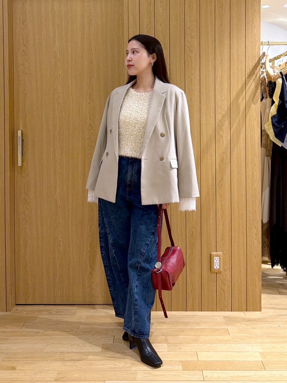 ブルー系のデニムパンツ、レッド系のハンドバッグ、ブラック系のブーツを着用したレディースの秋コーディネートの1枚目の写真