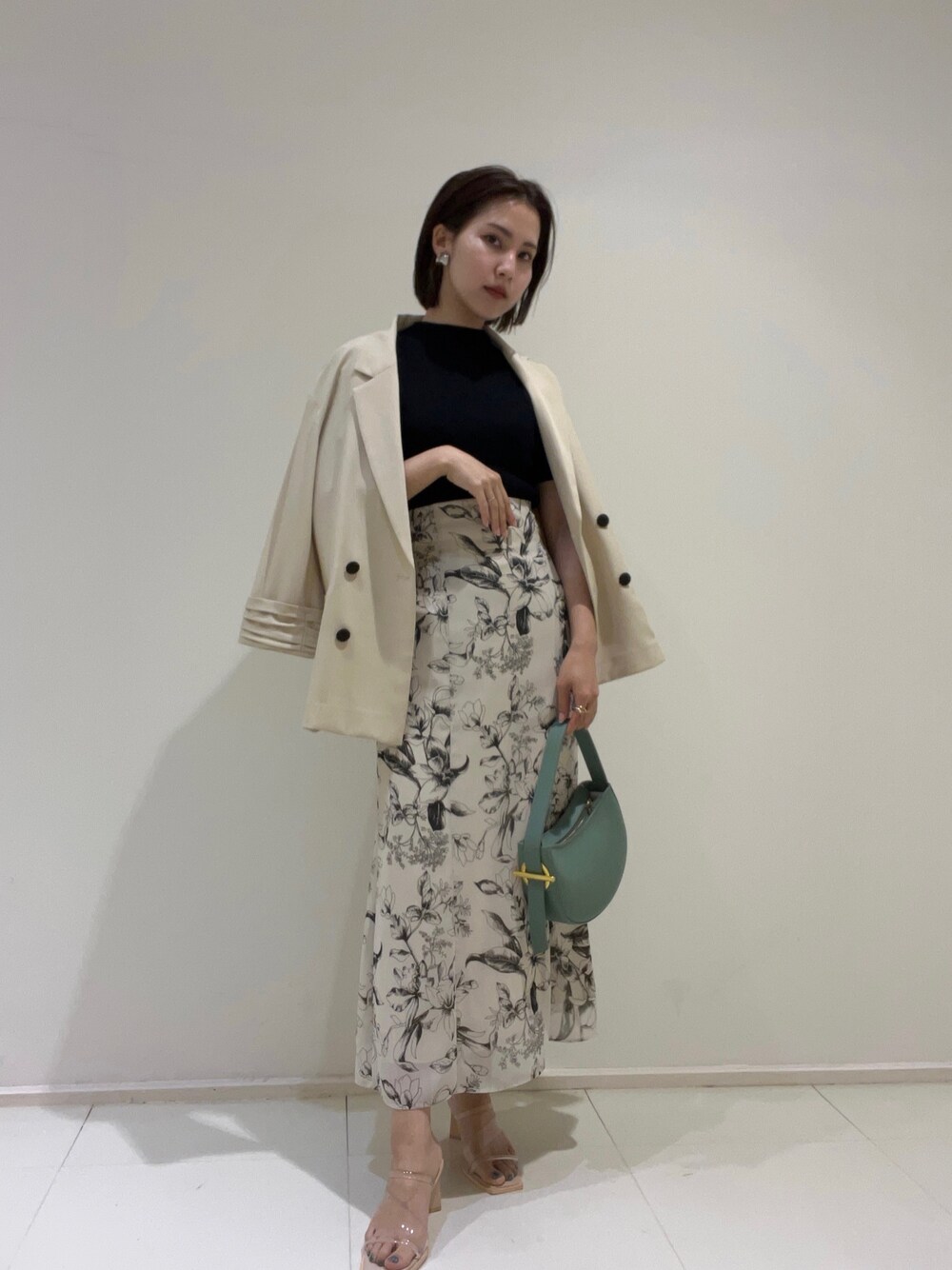 ベージュ系のテーラードジャケット、グリーン系のハンドバッグ、その他のサンダルを着用したレディースの春コーディネートの1枚目の写真