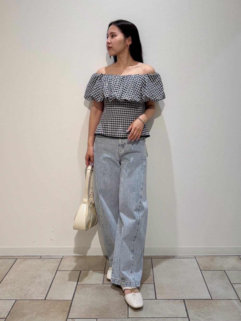 ブルー系のデニムパンツ、ホワイト系のサンダル、ホワイト系のハンドバッグを着用したレディースの夏コーディネートの1枚目の写真