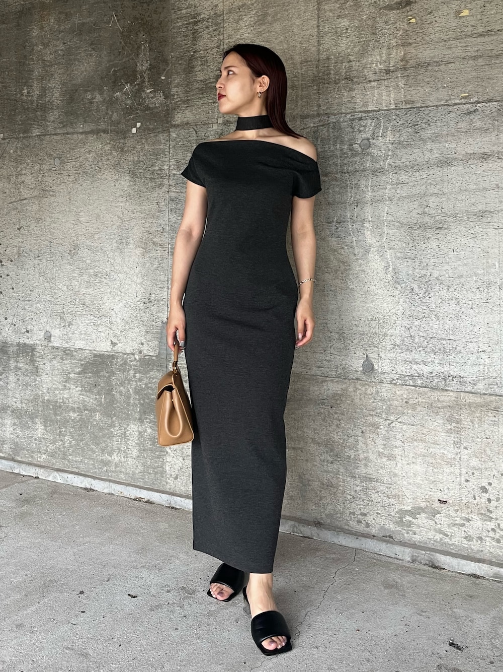 グレー系のワンピース、ブラウン系のハンドバッグ、ブラック系のサンダルを着用したレディースの夏コーディネートの1枚目の写真