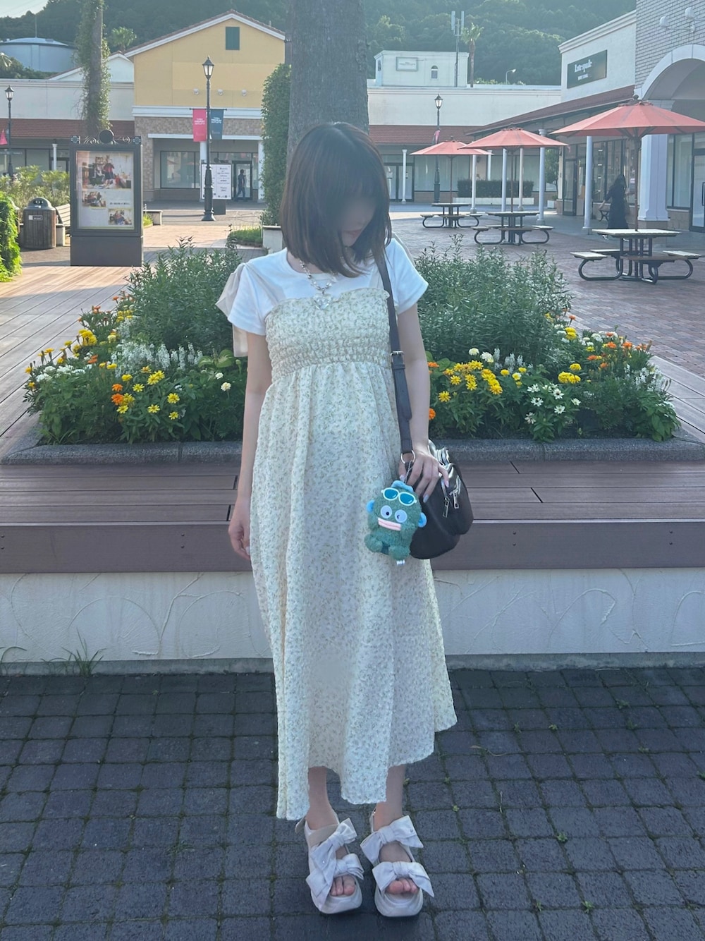 イエロー系のワンピース、ホワイト系のキーホルダーを着用したレディースの夏コーディネートの1枚目の写真