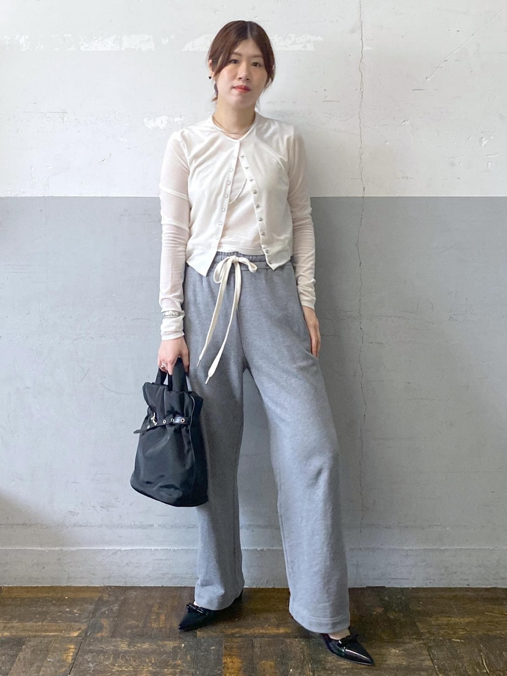 ブラック系のパンプス、ホワイト系のカーディガン/ボレロ、グレー系のスウェットパンツを着用したレディースの秋コーディネートの1枚目の写真