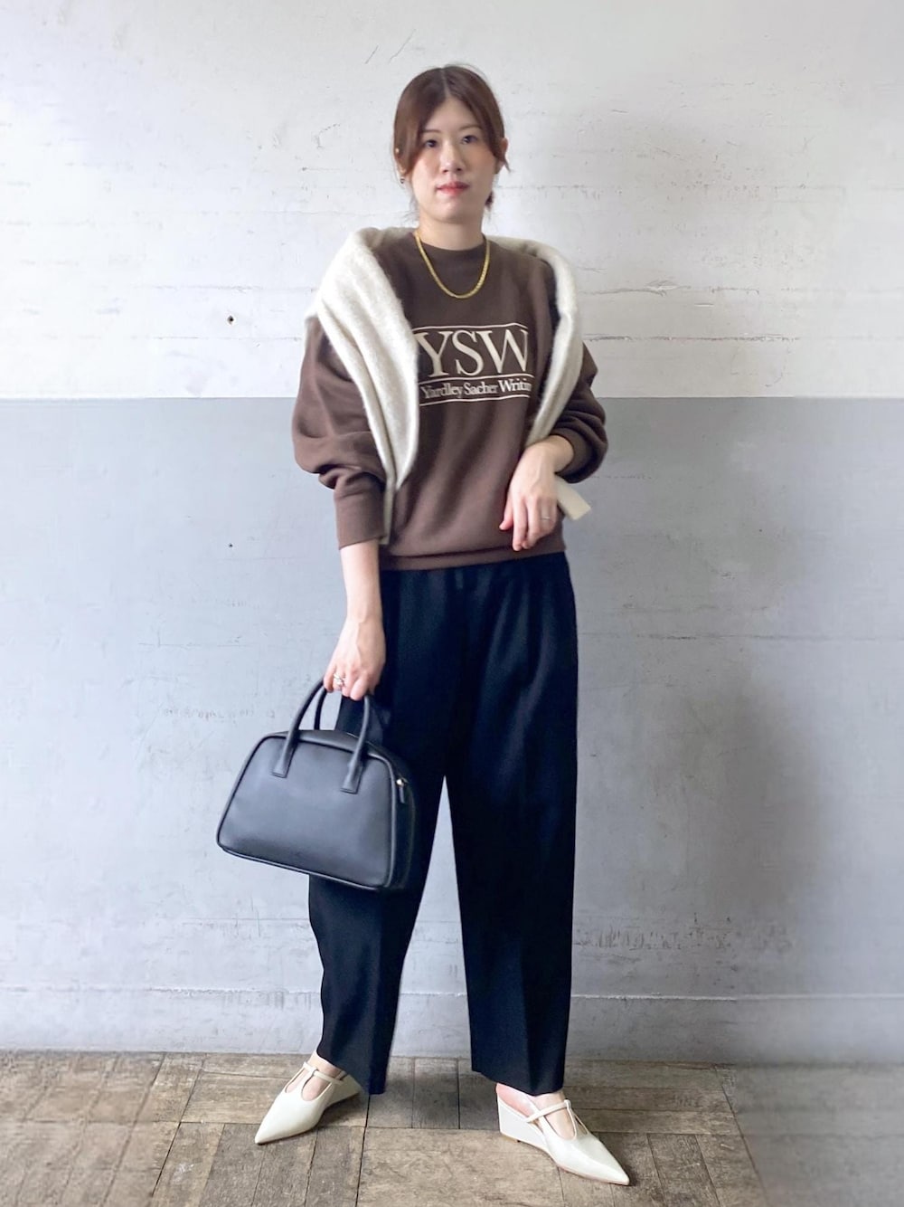ホワイト系のパンプス、ブラック系のスラックス、ブラック系のボストンバッグを着用したレディースの秋コーディネートの1枚目の写真
