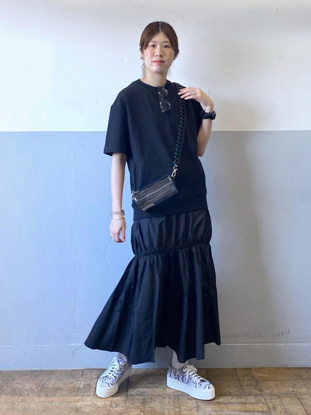 ブラック系のスニーカー、ブラック系のドラムバッグ、ブラック系のワンピースを着用したレディースの夏コーディネートの1枚目の写真