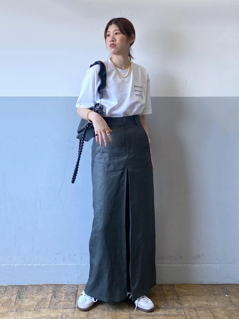 グレー系のスカート、ブラック系のショルダーバッグ、ホワイト系のTシャツ/カットソーを着用したレディースの夏コーディネートの1枚目の写真