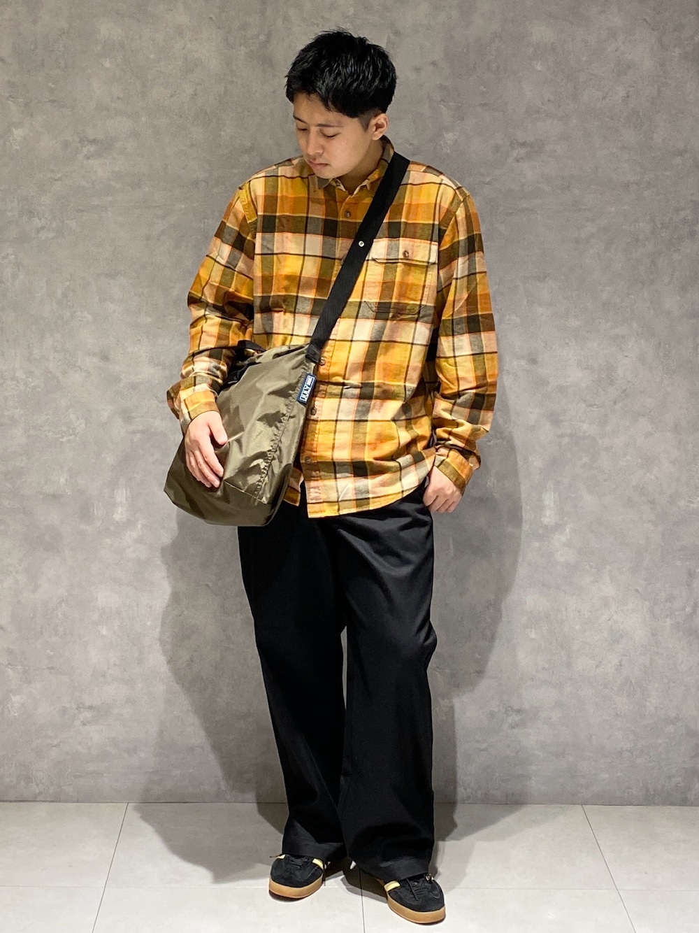 オレンジ系のシャツ/ブラウス、グリーン系のショルダーバッグ、ブラック系のチノパンツを着用したメンズの秋コーディネートの1枚目の写真