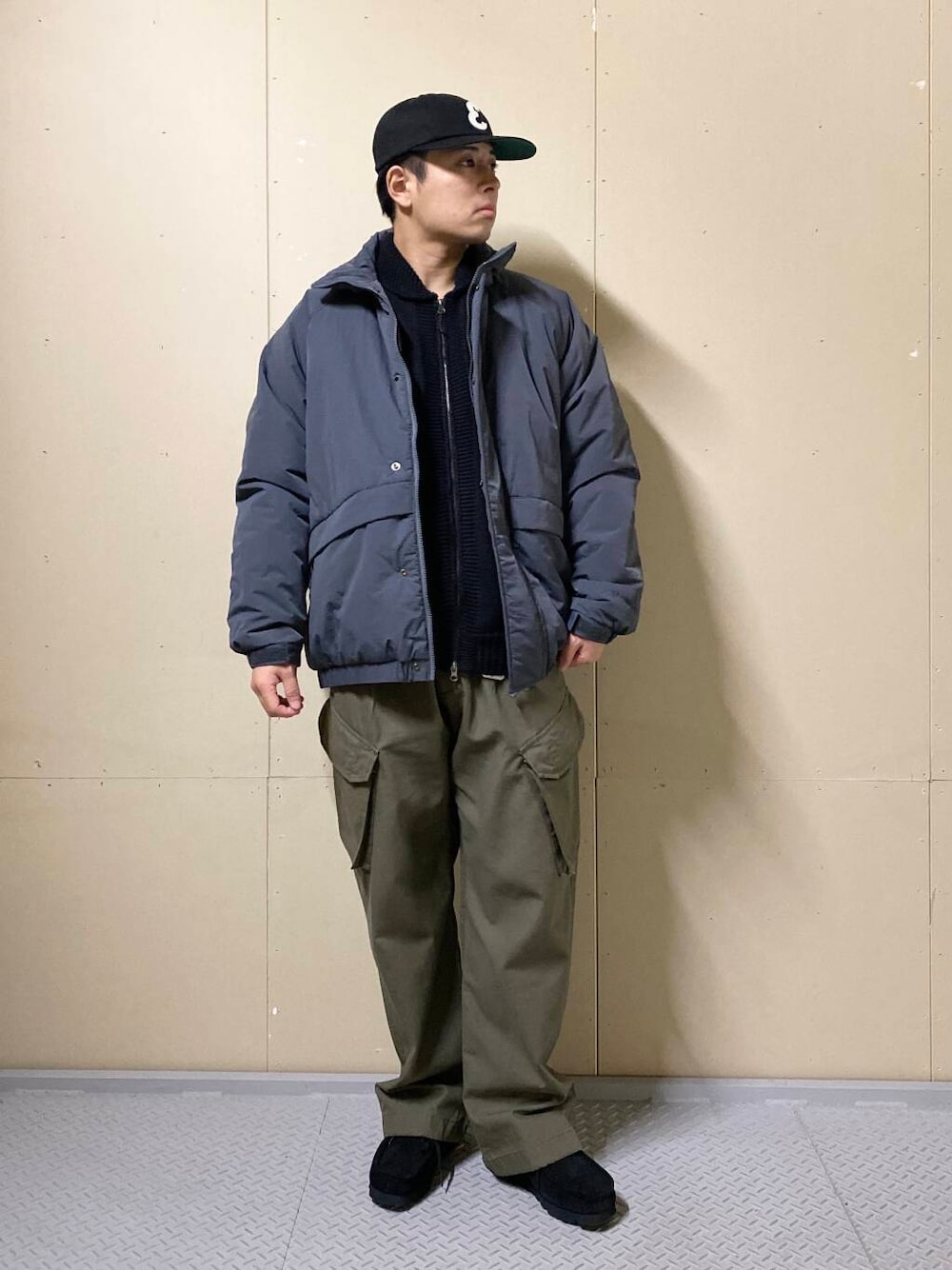 グリーン系のカーゴパンツ、ブラック系のブーツ、ブラック系のニット/セーターを着用したメンズの秋コーディネートの1枚目の写真