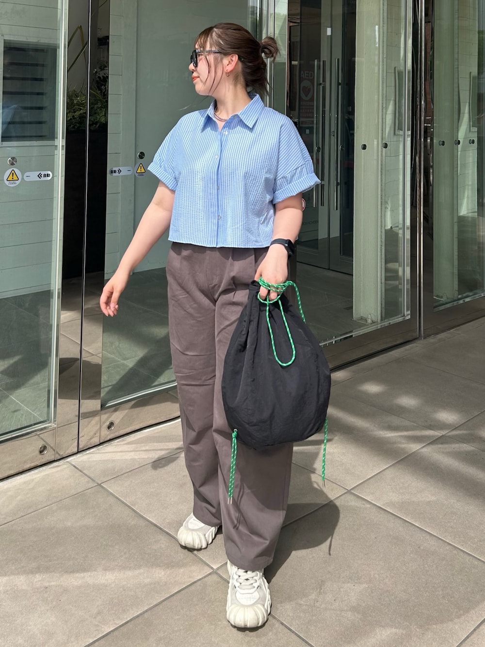 グレー系のチノパンツ、ブルー系のシャツ/ブラウス、ブラック系のバックパック/リュックを着用したレディースの春コーディネートの1枚目の写真