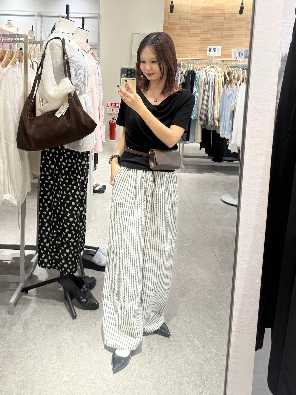 ブラック系のパンプス、ブラック系のTシャツ/カットソー、ブラウン系のボディバッグ/ウエストポーチを着用したレディースの春コーディネートの1枚目の写真