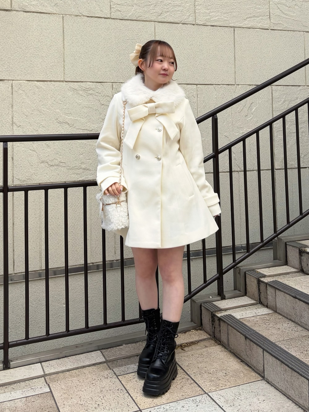 ホワイト系のステンカラーコート、ホワイト系のショルダーバッグ、ブラック系のブーツを着用したレディースの冬コーディネートの1枚目の写真