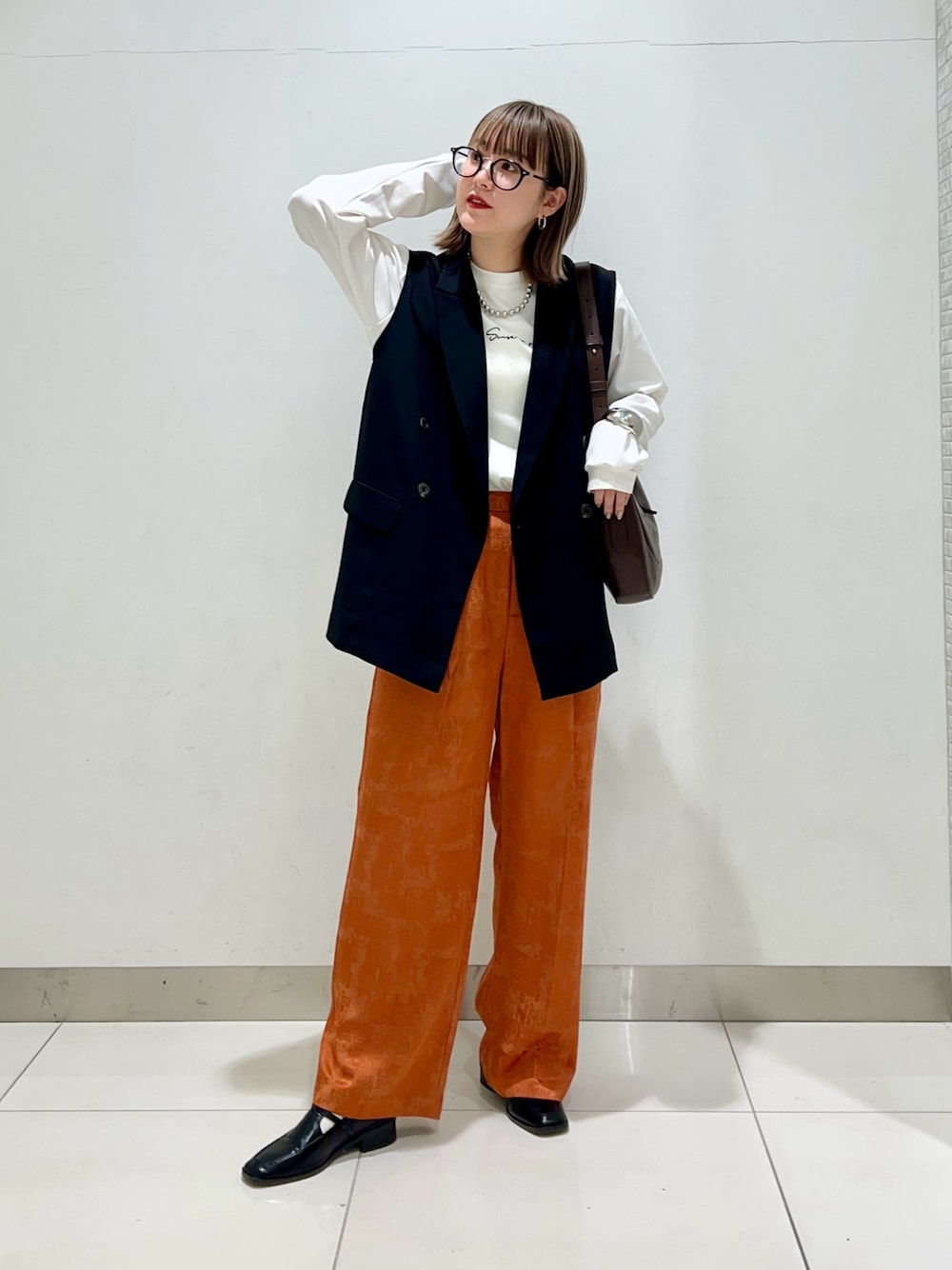 ブラウン系のショルダーバッグ、ブラック系のその他アウター、オレンジ系のその他パンツを着用したレディースの春コーディネートの1枚目の写真