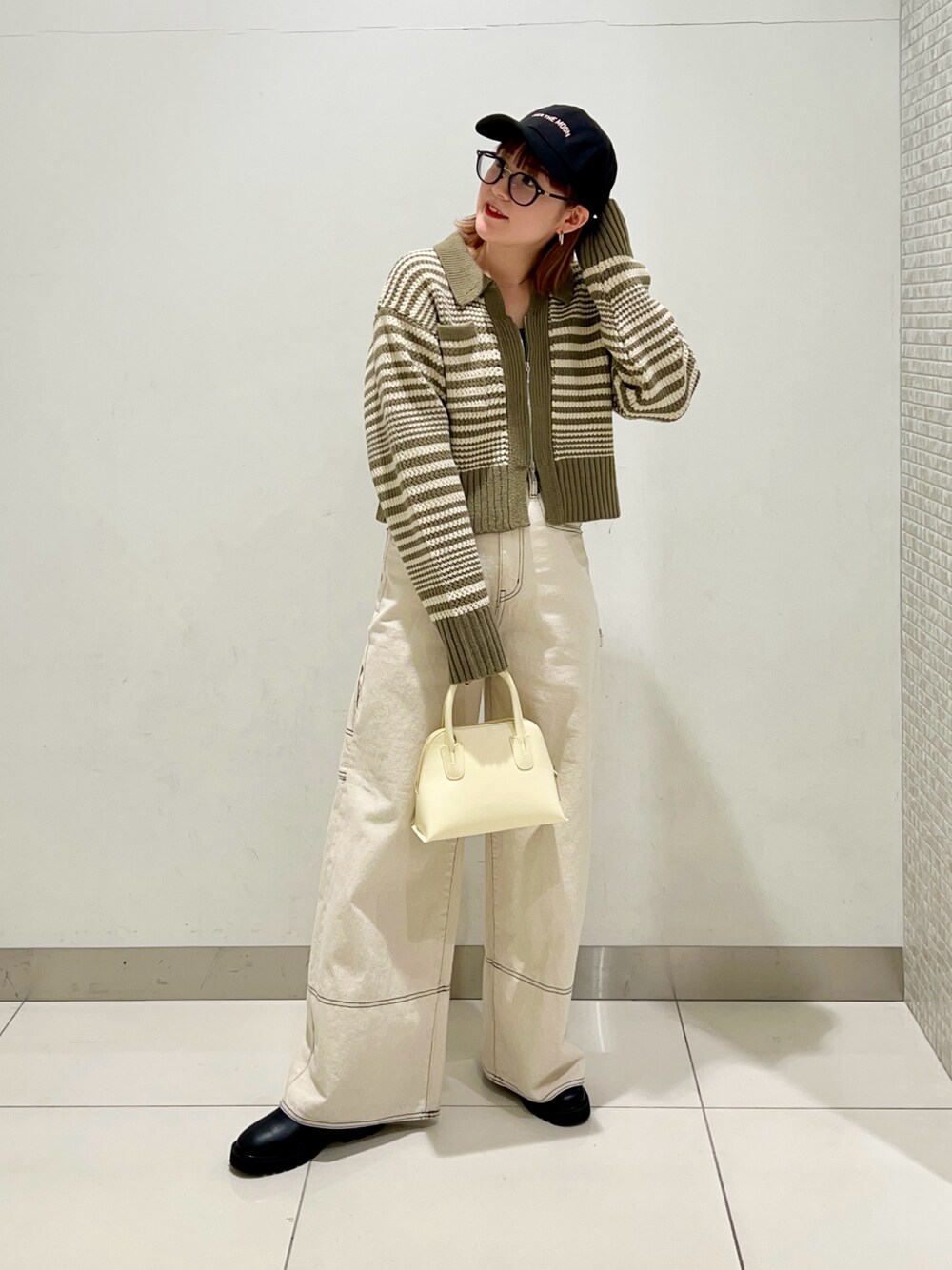 グリーン系のニット/セーター、ホワイト系のデニムパンツ、イエロー系のショルダーバッグを着用したレディースの冬コーディネートの1枚目の写真