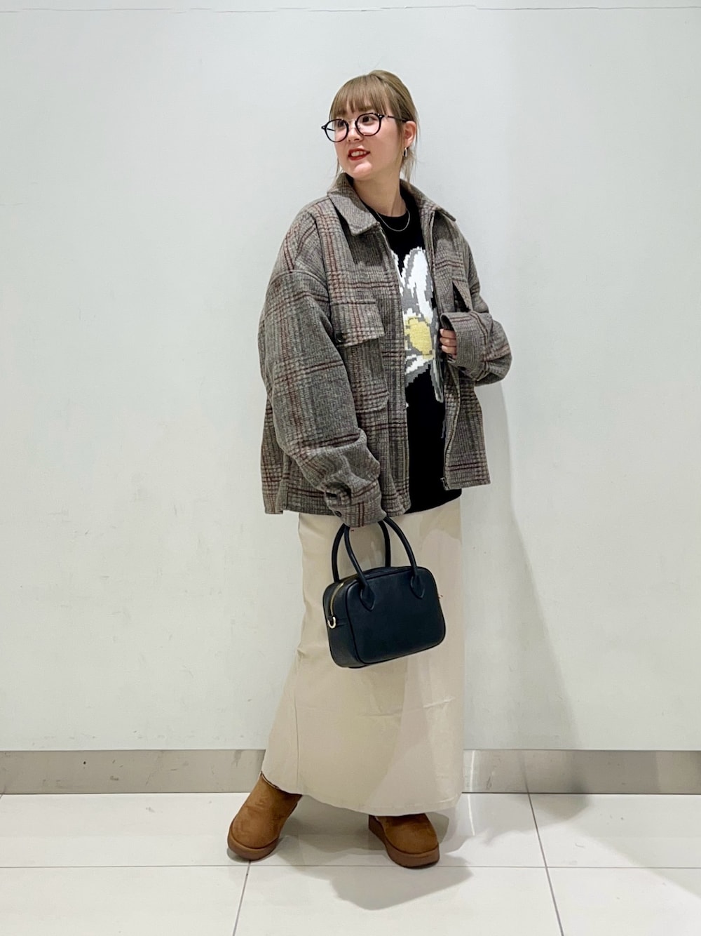ブラック系のボストンバッグ、ベージュ系のスカート、ブラック系のニット/セーターを着用したレディースの冬コーディネートの1枚目の写真