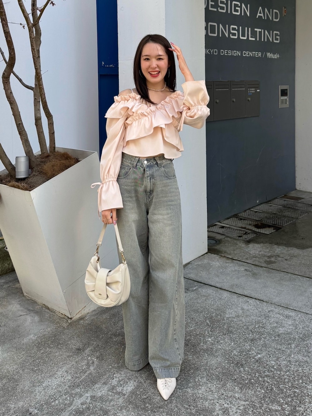 ブルー系のデニムパンツ、ピンク系のシャツ/ブラウス、ホワイト系のショルダーバッグを着用したレディースの春コーディネートの1枚目の写真