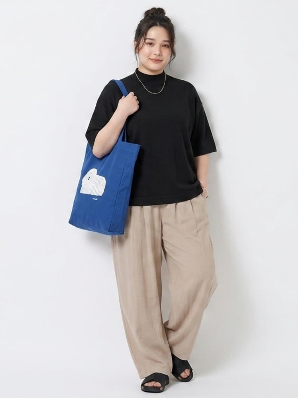ベージュ系のパンツ、ブルー系のトートバッグ、ブラック系のニット/セーターを着用したレディースの夏コーディネートの1枚目の写真
