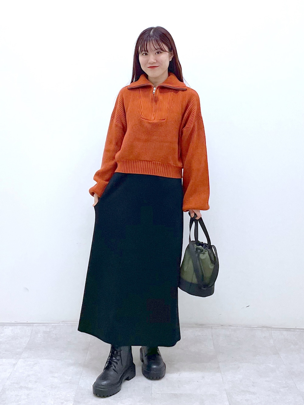 ブラック系のブーツ、ブラック系のワンピース、オレンジ系のニット/セーターを着用したレディースの秋コーディネートの1枚目の写真