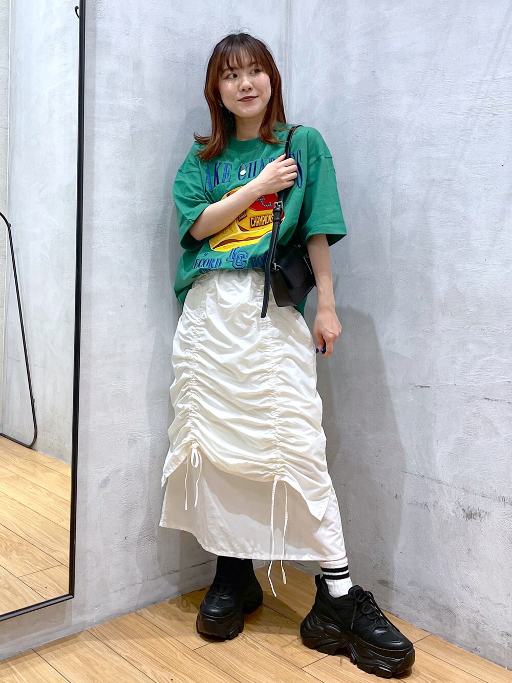 ブラック系のスニーカー、ホワイト系のスカート、ブラック系のハンドバッグを着用したレディースの春コーディネートの1枚目の写真