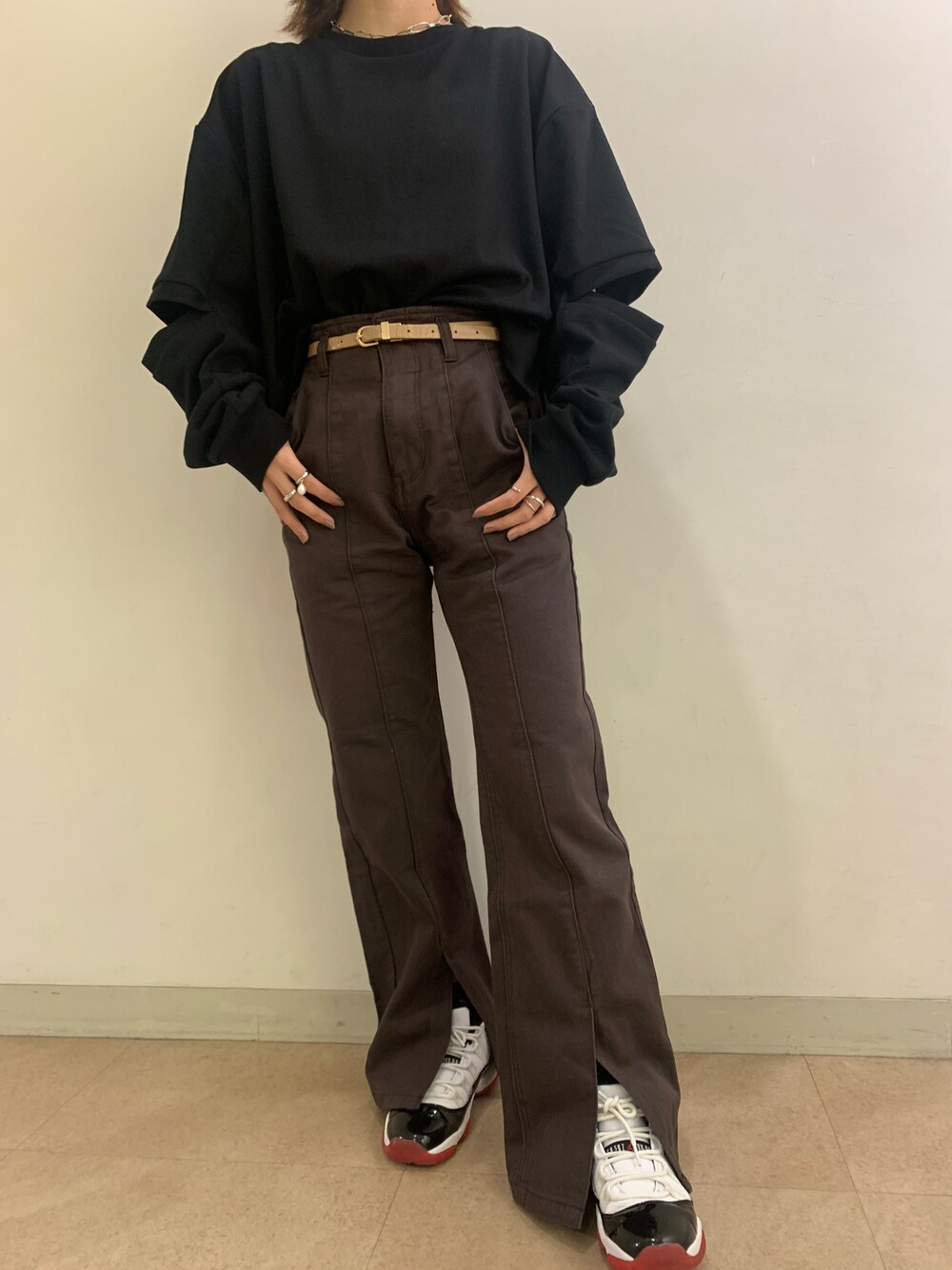 ブラウン系のデニムパンツ、ブラック系のトップス、ホワイト系のシューズを着用したレディースの秋コーディネートの1枚目の写真