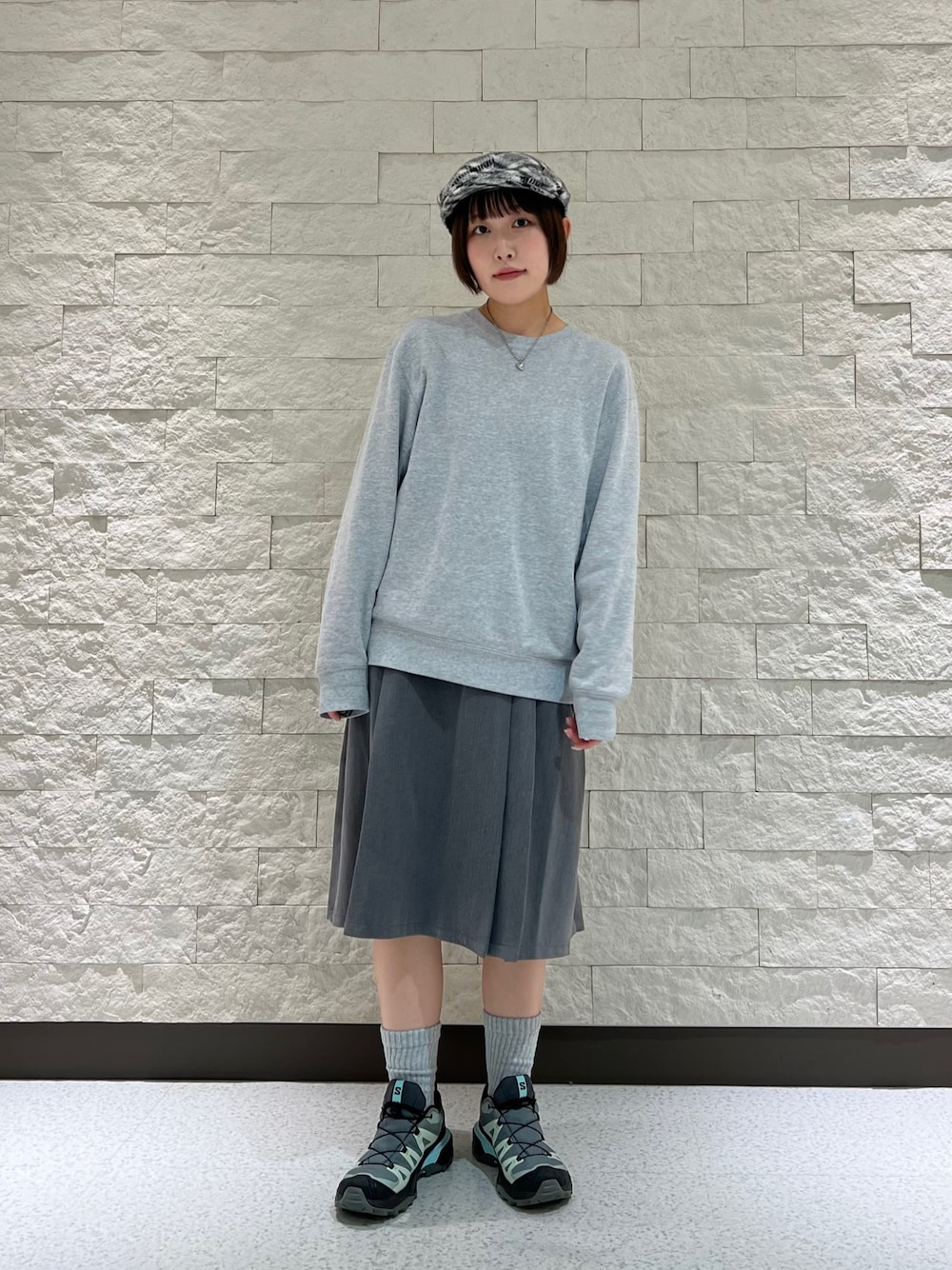 グレー系のスウェット、グレー系のスニーカー、ブラック系のハンチング/ベレー帽を着用したレディースの秋コーディネートの1枚目の写真