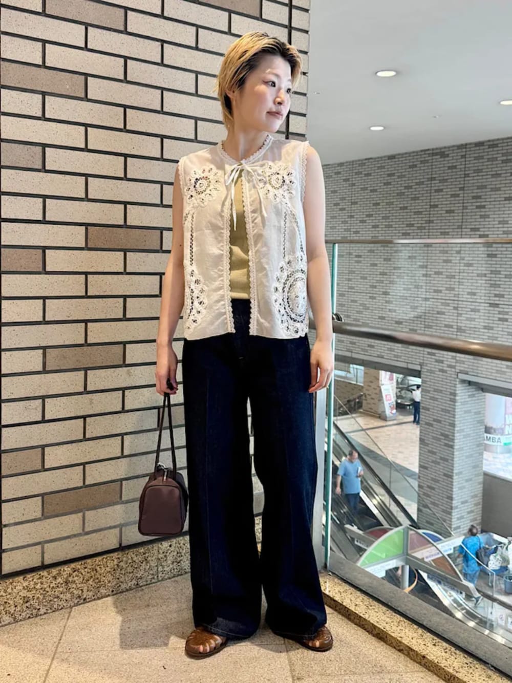ブルー系のデニムパンツ、ブラウン系のショルダーバッグを着用したレディースの夏コーディネートの1枚目の写真
