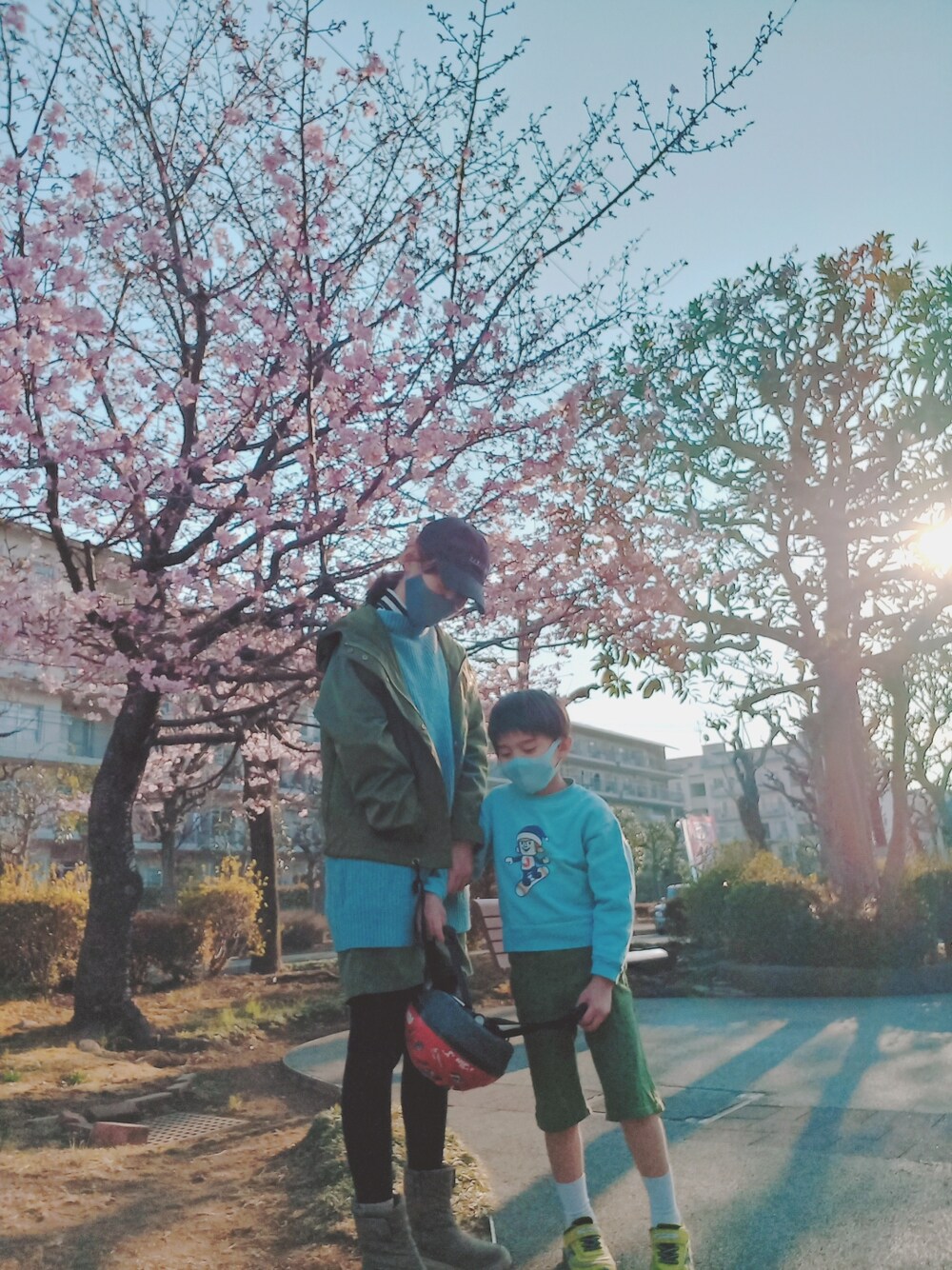 グリーン系のマウンテンパーカー、ホワイト系のトップス、ブルー系のニット/セーターを着用したキッズの春コーディネートの4枚目の写真