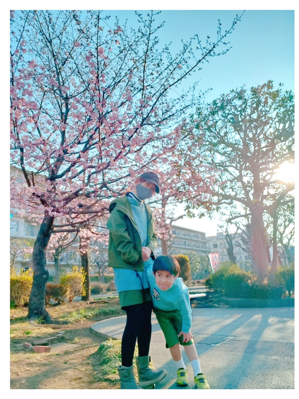 グリーン系のマウンテンパーカー、ホワイト系のトップス、ブルー系のニット/セーターを着用したキッズの春コーディネートの2枚目の写真