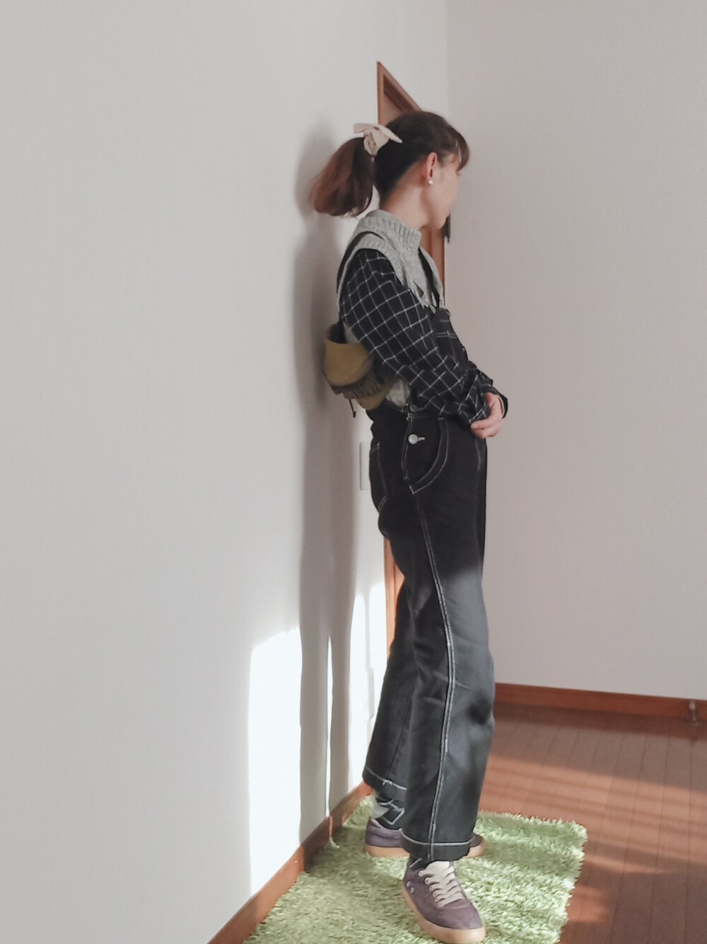 グレー系のニット/セーター、ブラック系のサロペット/オーバーオール、グリーン系のボディバッグ/ウエストポーチを着用したレディースの冬コーディネートの2枚目の写真
