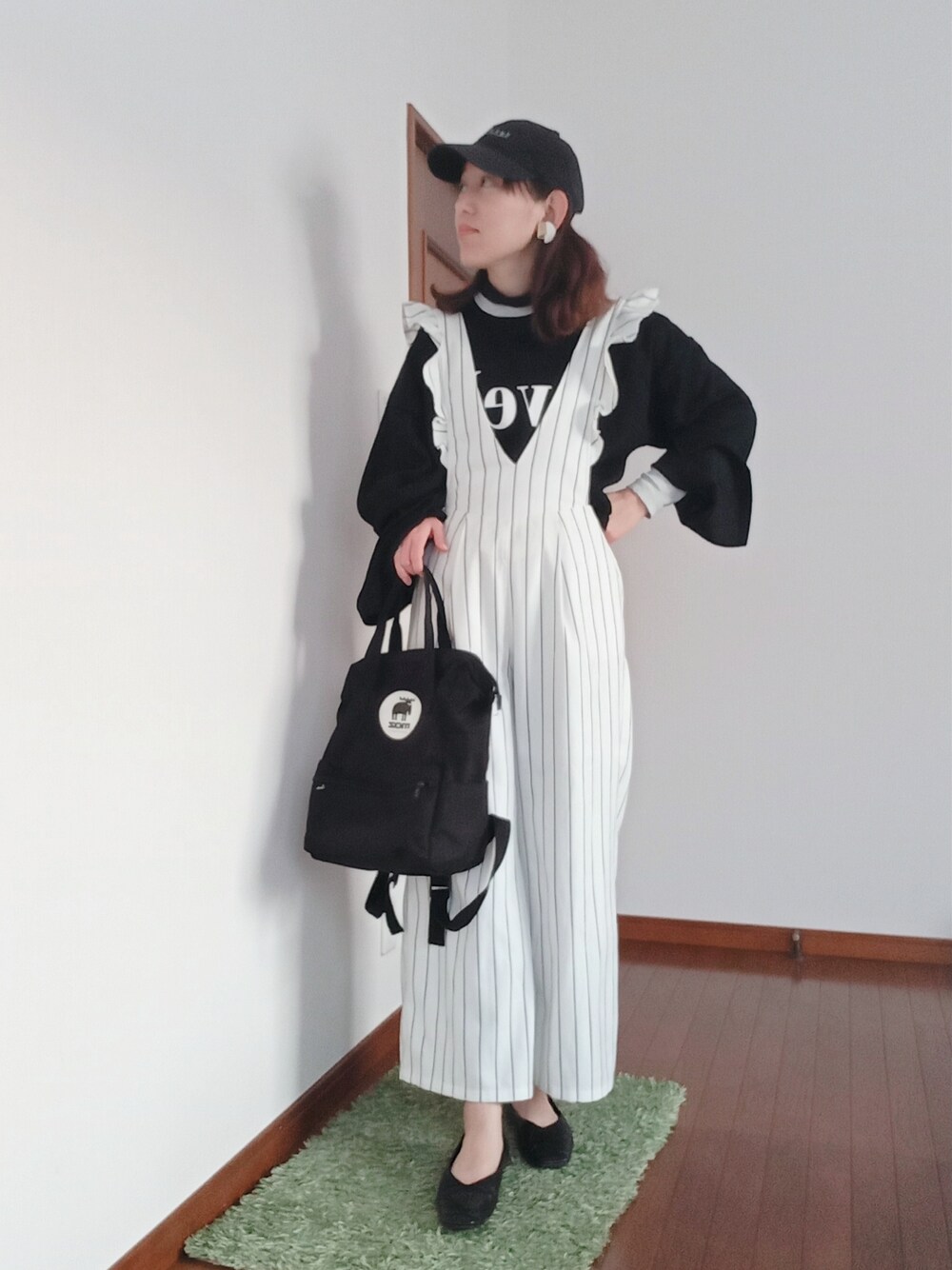 ブラック系のニット/セーター、ホワイト系のオールインワン・サロペット、ブラック系のバックパック/リュックを着用したレディースの冬コーディネートの2枚目の写真