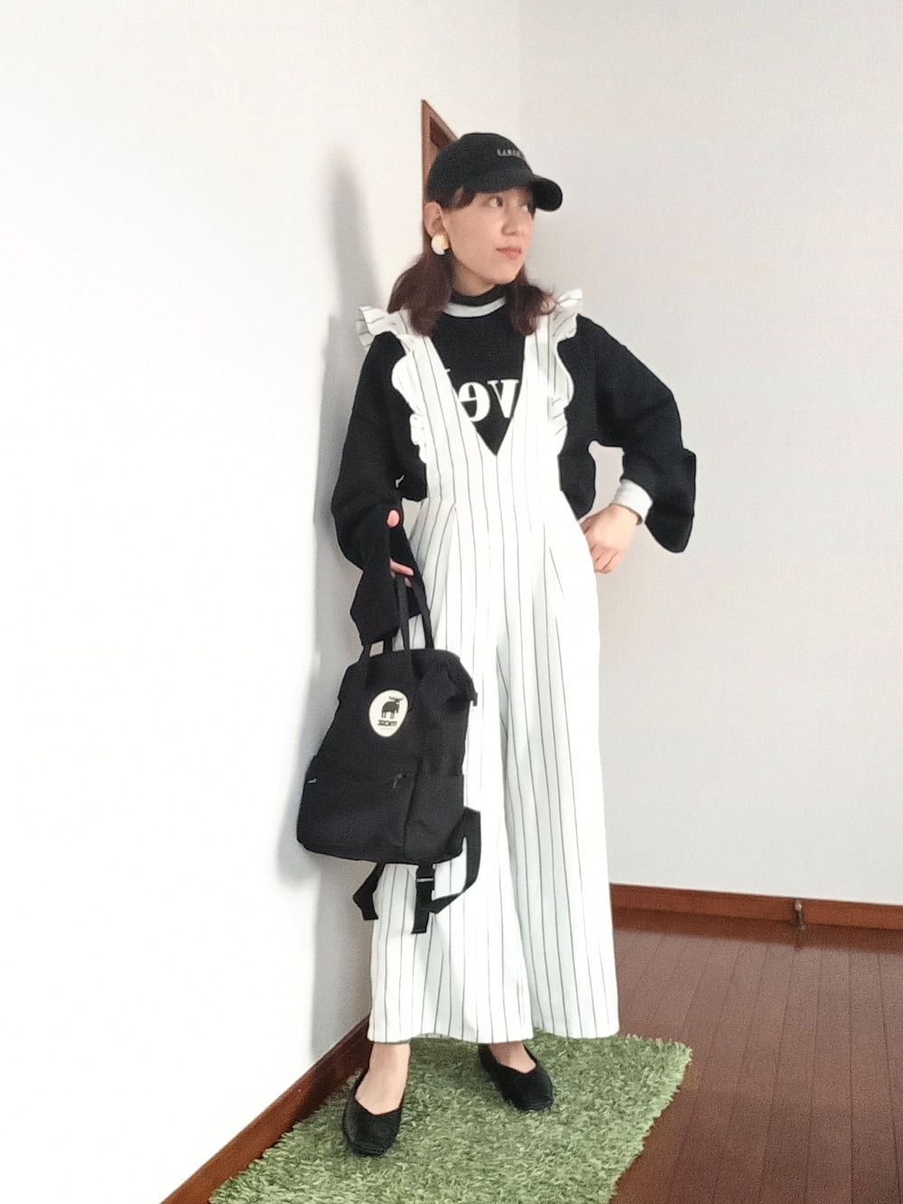 ブラック系のニット/セーター、ホワイト系のオールインワン・サロペット、ブラック系のバックパック/リュックを着用したレディースの冬コーディネートの3枚目の写真