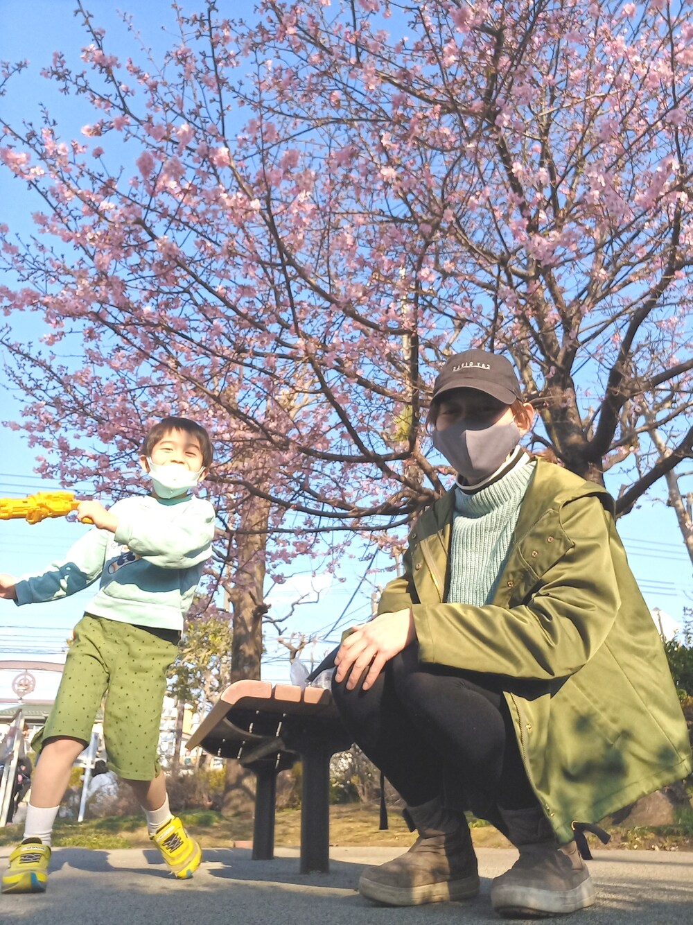 グリーン系のマウンテンパーカー、ホワイト系のトップス、ブルー系のニット/セーターを着用したキッズの春コーディネートの3枚目の写真