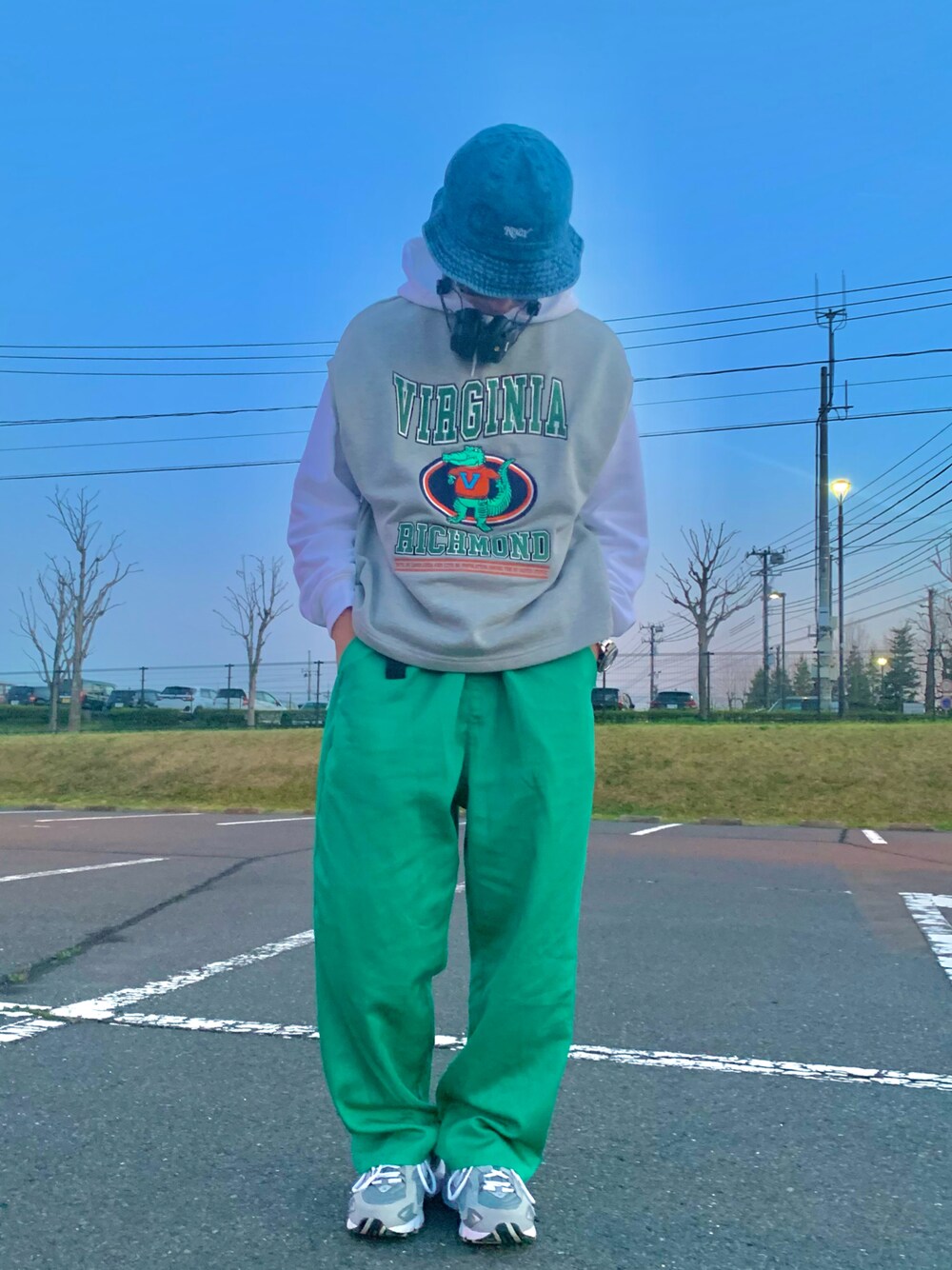 グレー系のベスト、グリーン系のチノパンツ、グレー系のスニーカーを着用したメンズの春コーディネートの1枚目の写真