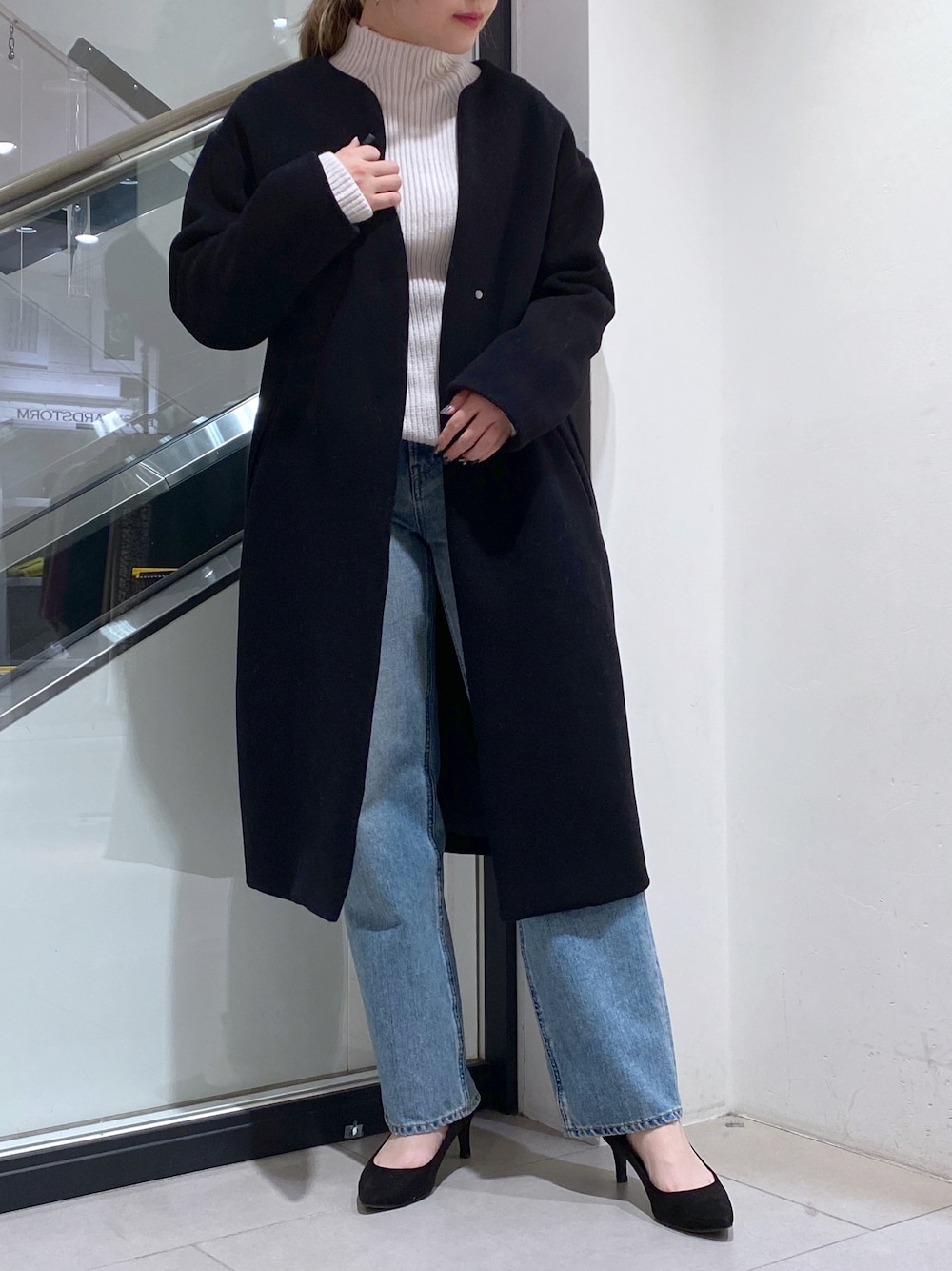 ブルー系のデニムパンツ、ホワイト系のニット/セーター、ブラック系のその他アウターを着用したレディースの冬コーディネートの1枚目の写真