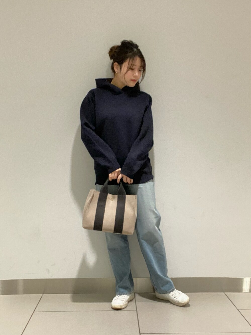 ホワイト系のニット/セーター、ブルー系のデニムパンツ、ベージュ系のショルダーバッグを着用したレディースの冬コーディネートの1枚目の写真