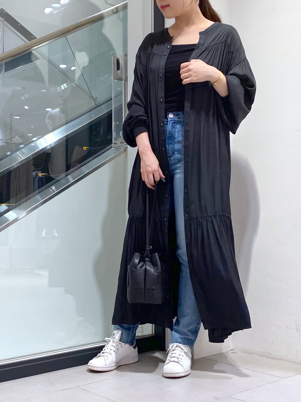 ホワイト系のスニーカー、ブルー系のデニムパンツ、ホワイト系のショルダーバッグを着用したレディースの秋コーディネートの1枚目の写真