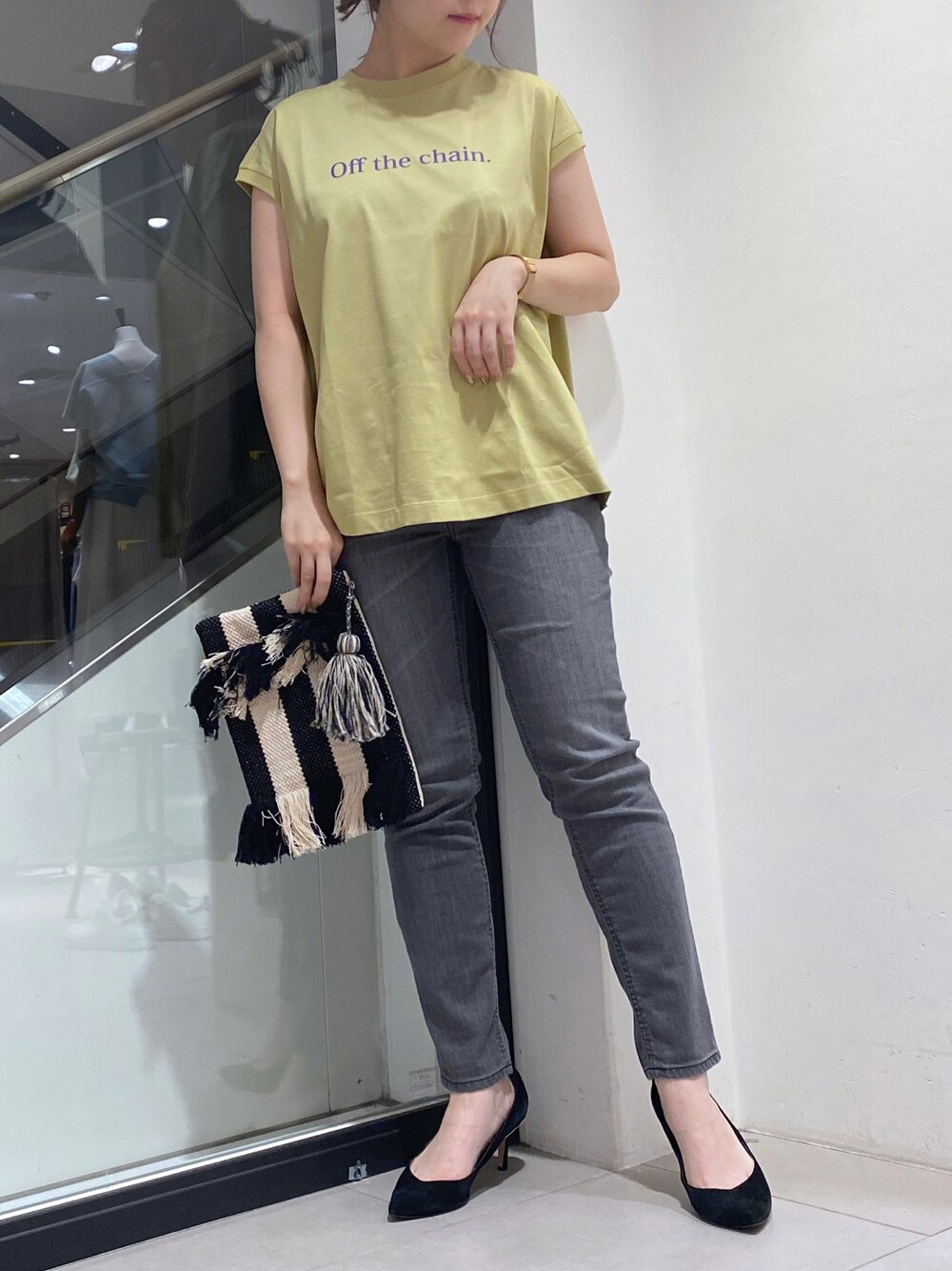 グレー系のデニムパンツ、ブラック系のクラッチバッグ、ホワイト系のTシャツ/カットソーを着用したレディースの夏コーディネートの1枚目の写真