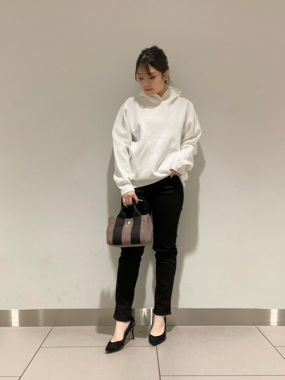 ブラック系のトートバッグ、ホワイト系のニット/セーター、ブラック系のデニムパンツを着用したレディースの冬コーディネートの1枚目の写真