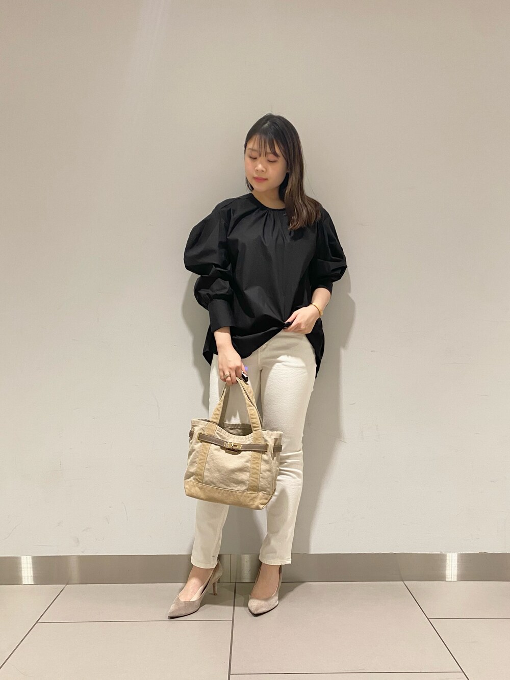 ベージュ系のショルダーバッグ、ブラック系のシャツ/ブラウス、ホワイト系のデニムパンツを着用したレディースの春コーディネートの1枚目の写真