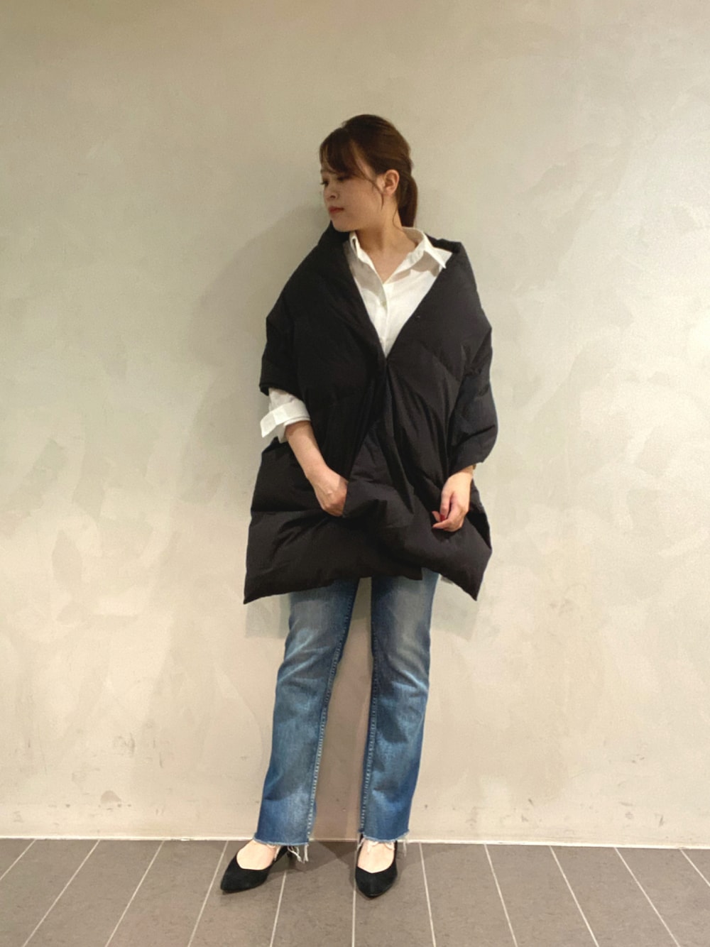 ブルー系のデニムパンツ、ブラック系のダウンベスト、ベージュ系のシャツ/ブラウスを着用したレディースの秋コーディネートの1枚目の写真