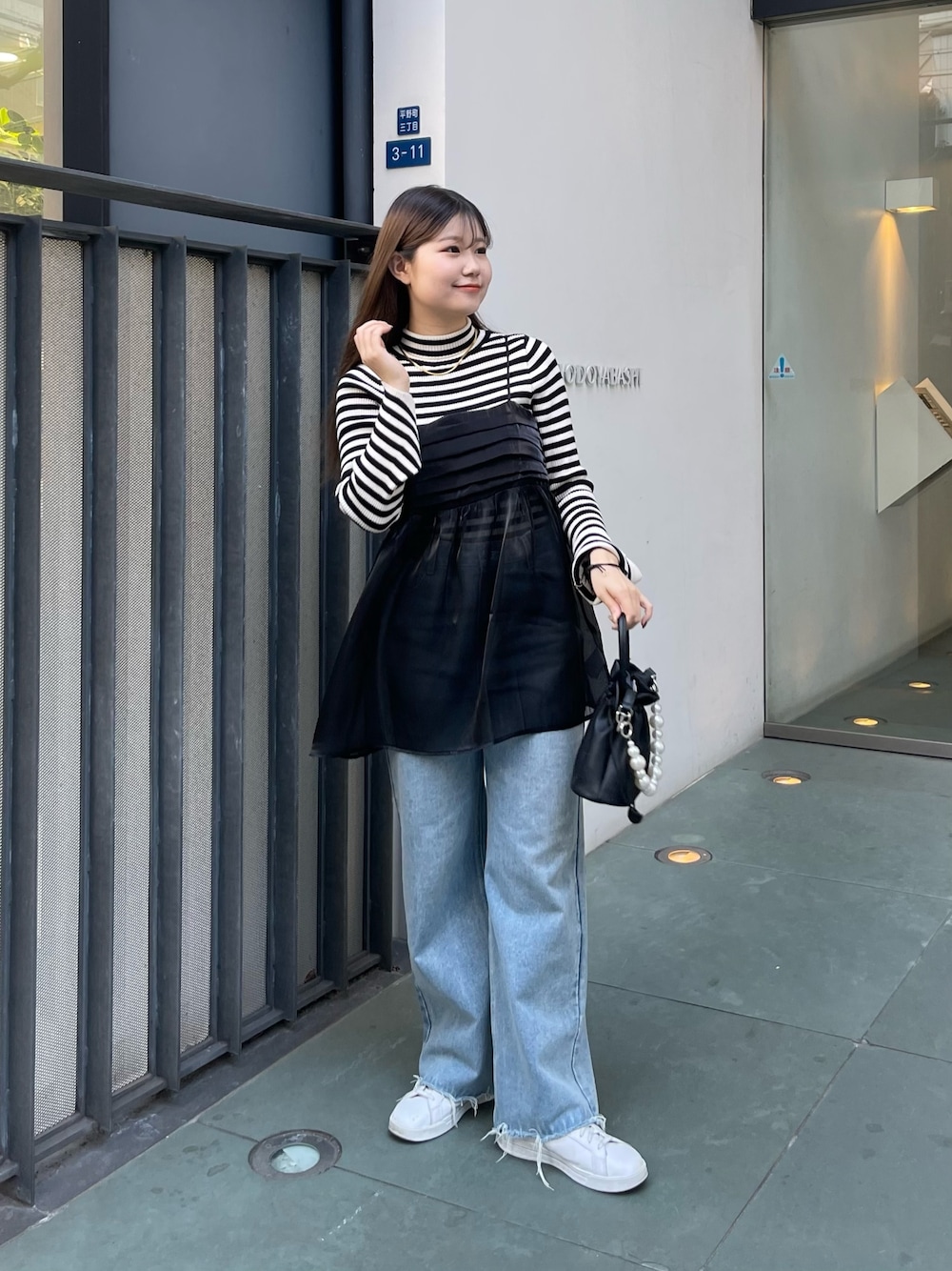 ホワイト系のニット/セーター、ブラック系のショルダーバッグ、ブラック系のキャミソールを着用したレディースの冬コーディネートの1枚目の写真